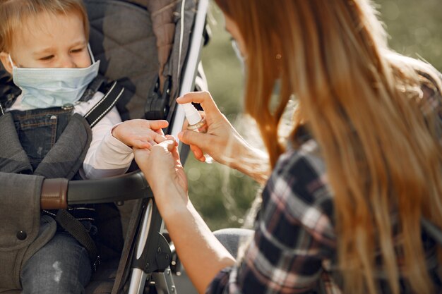 Moeder die gezichtsmasker draagt. Moeder met baby kinderwagen tijdens pandemie buiten wandelen.