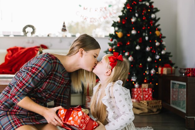 Moeder die haar dochter kust bij Kerstmis