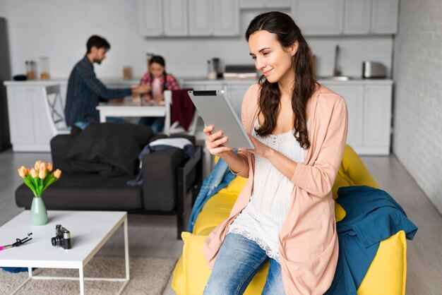 Moeder die tablet en familie gebruikt aan de tafel