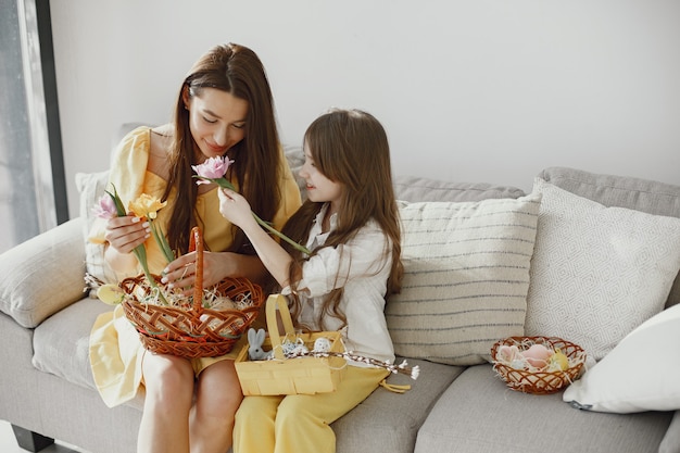 Moeder en dochter bereiden zich voor op Pasen thuis op de bank in gele kleren