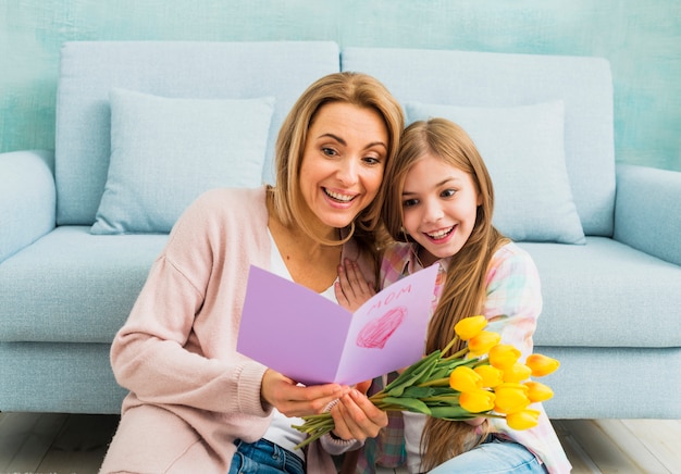 Gratis foto moeder en dochter die en de prentbriefkaar van de moeder` s dag glimlachen lezen