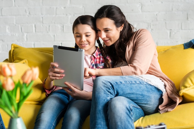 Moeder en dochter die op een digitale tablet kijken