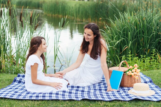 Moeder en dochter die van picknick door het meer genieten