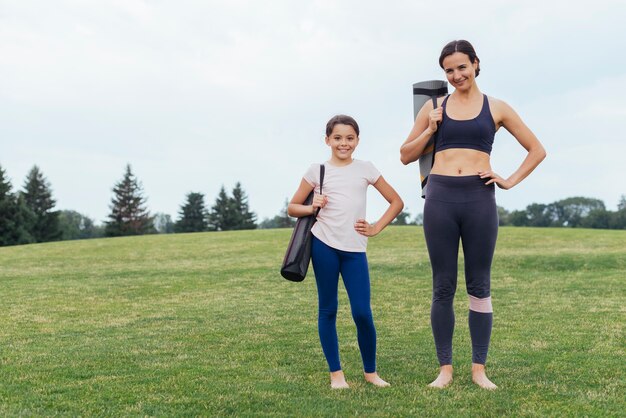 Moeder en dochter die yogamatten dragen