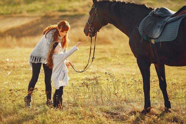 Moeder en dochter in een veld spelen met een paard