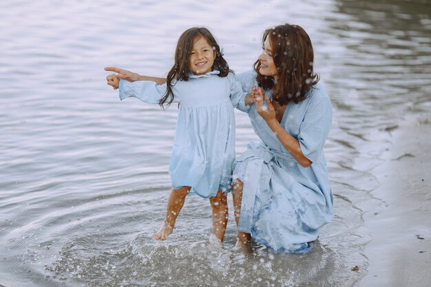 Moeder en dochter in identieke jurken. Familie spelen bij de rivier.
