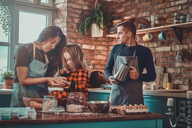 Moeder en dochter koken iets lekkers terwijl vader 's ochtends koffie bereidt.