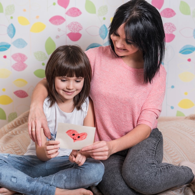 Moeder en dochter lezen wenskaart op bed