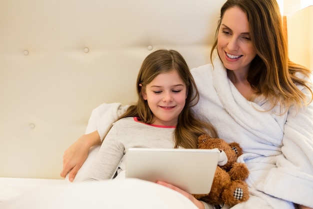 Moeder en dochter met behulp van digitale tablet in de slaapkamer