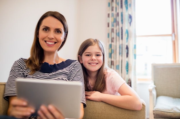 Moeder en dochter met behulp van digitale tablet in woonkamer