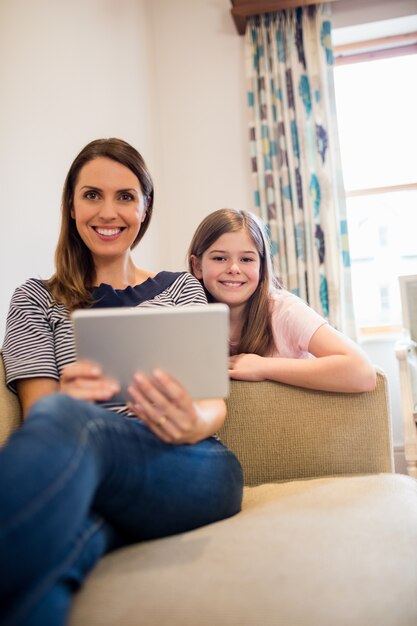 Moeder en dochter met behulp van digitale tablet in woonkamer