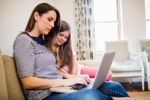 Moeder en dochter met behulp van laptop in de woonkamer