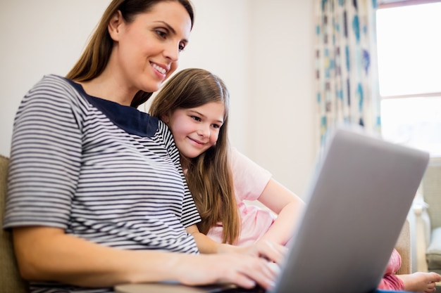 Moeder en dochter met behulp van laptop in de woonkamer