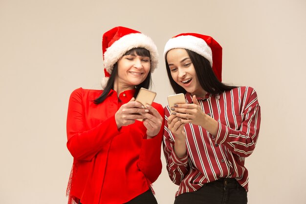 Moeder en dochter met kerstmuts met behulp van smartphones