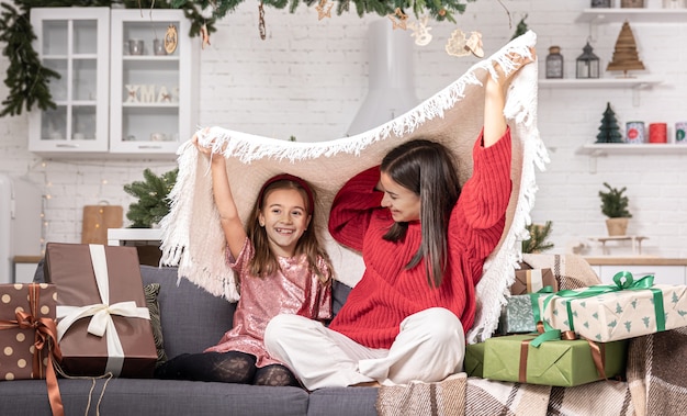 Moeder en dochter op de bank in de kamer tussen de kerstcadeaus.