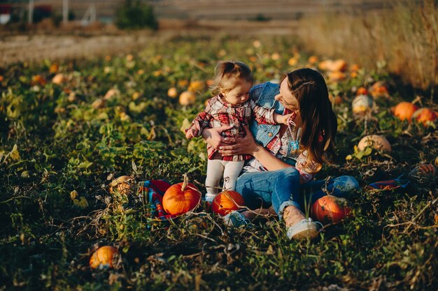 Moeder en dochter op een veld met pompoenen, Halloween vooravond