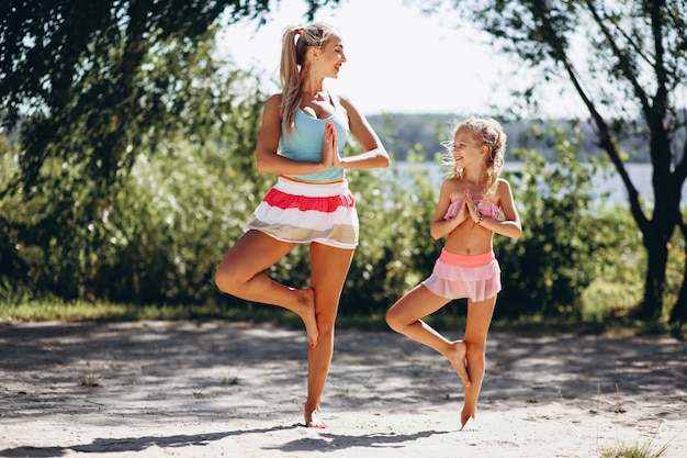 Moeder en dochter op het strand beoefenen van yoga