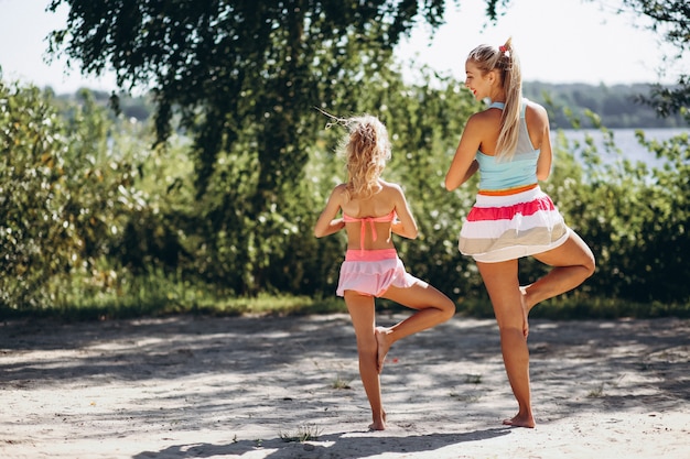 Moeder en dochter op het strand beoefenen van yoga