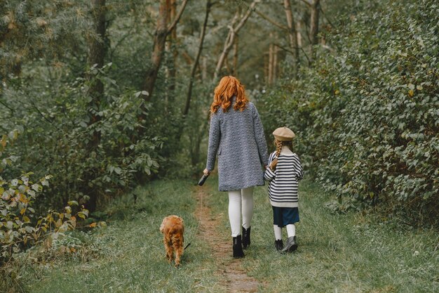 Moeder en haar dochter spelen met hond. Familie in de herfstpark. Huisdier, huisdier en levensstijl concept. Herfst tijd.