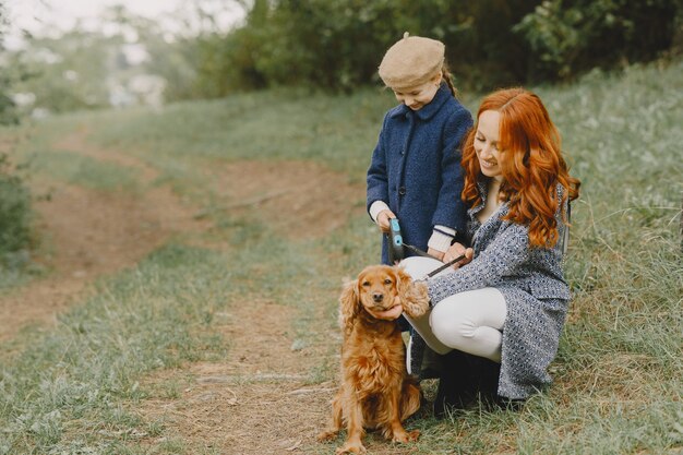 Moeder en haar dochter spelen met hond. Familie in de herfstpark. Huisdier, huisdier en levensstijl concept. Herfst tijd.