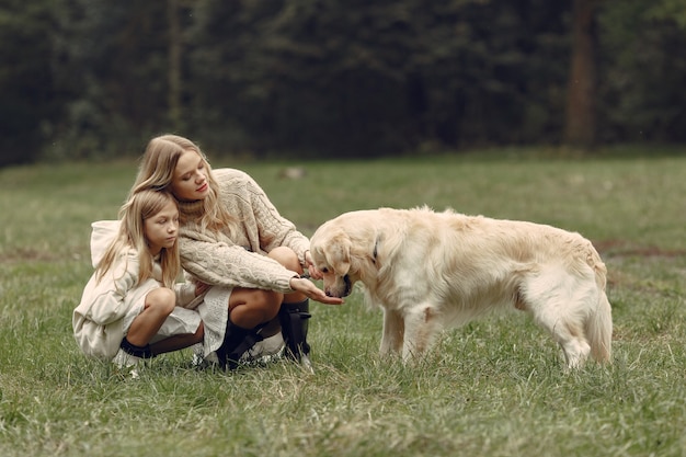 Moeder en haar dochter spelen met hond. Familie in de herfstpark. Huisdier, huisdier en levensstijl concept