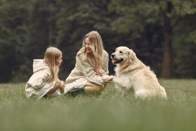 Moeder en haar dochter spelen met hond. Familie in de herfstpark. Huisdier, huisdier en levensstijl concept