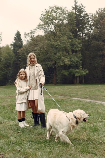 Moeder en haar dochter spelen met hond. Familie in de herfstpark. Huisdier, huisdier en levensstijl concept