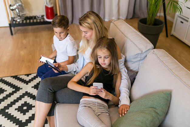 Moeder en haar kinderen kijken naar hun telefoons