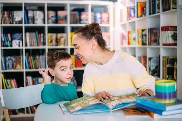 Moeder en haar kleine kind de kleuterzoon lezen samen kinderboeken