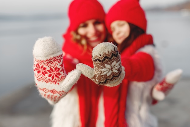 Moeder en kind in gebreide wintermutsen op familiekerstvakantie. handgemaakte wollen muts en sjaal voor mama en kind. breien voor kinderen. brei bovenkleding. vrouw en meisje in een park.