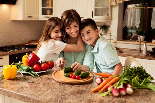 Moeder en kinderen in de keuken die voedsel voorbereidt