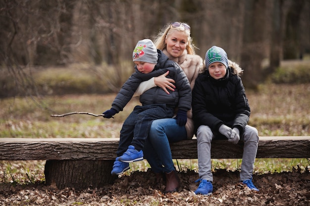 Moeder en kinderen zitten buiten op een houten bankje