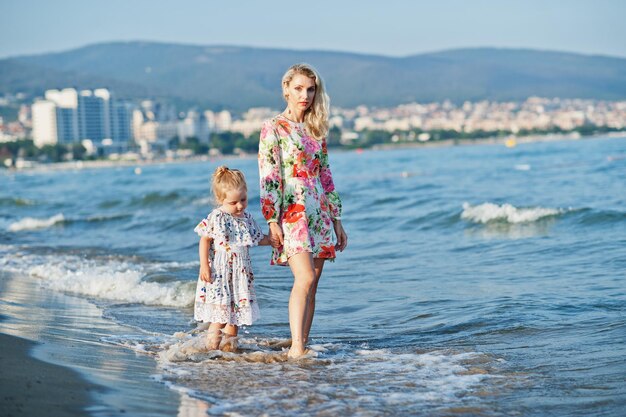 Moeder en mooie dochter die plezier hebben op het strand Portret van een gelukkige vrouw met een schattig klein meisje op vakantie