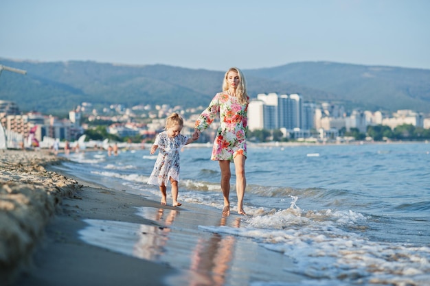 Moeder en mooie dochter die plezier hebben op het strand Portret van een gelukkige vrouw met een schattig klein meisje op vakantie