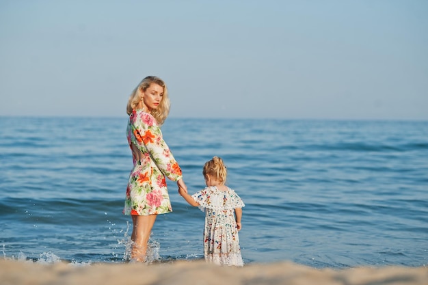 Moeder en mooie dochter die plezier hebben op het strand Portret van een gelukkige vrouw met een schattig klein meisje op vakantie