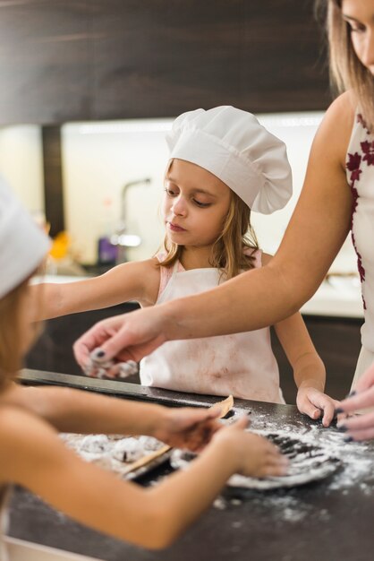 Moeder en twee dochters die koekjes in keuken voorbereiden