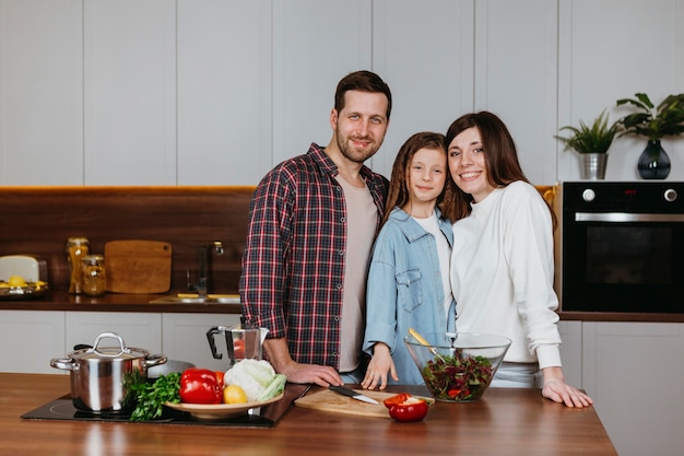 Moeder en vader met dochter poseren in de keuken