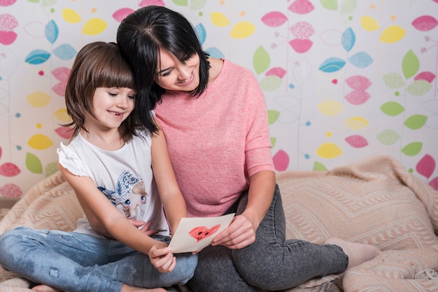 Moeder en weinig dochter die groetkaart lezen