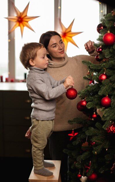 Moeder en zoon die de kerstboom versieren