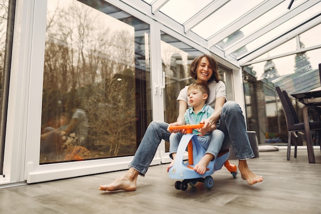 Moeder en zoon gaan rond in het appartement op een speelgoedauto