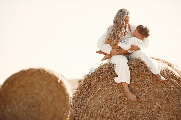 Moeder en zoon. Hooistapel of baal op geel tarwegebied in de zomer. Kinderen hebben samen plezier.