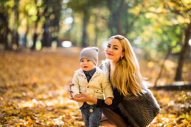 Moeder en zoontje in park of bos, buitenshuis. Samen knuffelen en plezier maken in het herfstpark