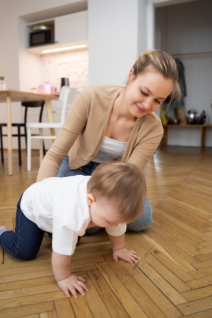 Gratis foto moeder helpt baby volledig schot te kruipen