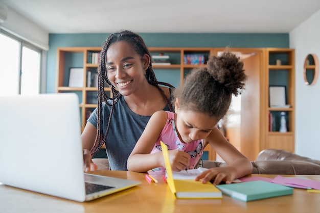 Moeder helpt en ondersteunt haar dochter met online school terwijl ze thuis blijft. Nieuw normaal levensstijlconcept. Monoparentaal concept.