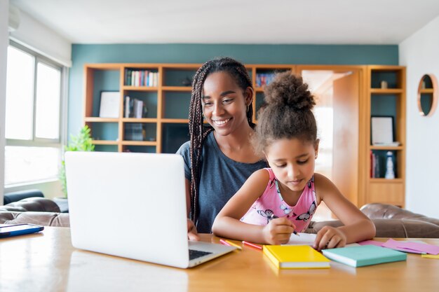 Moeder helpt en ondersteunt haar dochter met online school terwijl ze thuis blijft. Nieuw normaal levensstijlconcept. Monoparentaal concept.