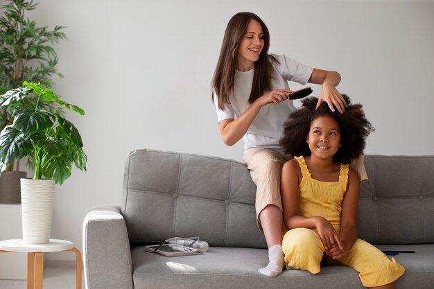 Gratis foto moeder helpt haar kind afro-haar te stylen