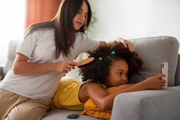 Gratis foto moeder helpt haar kind afro-haar te stylen