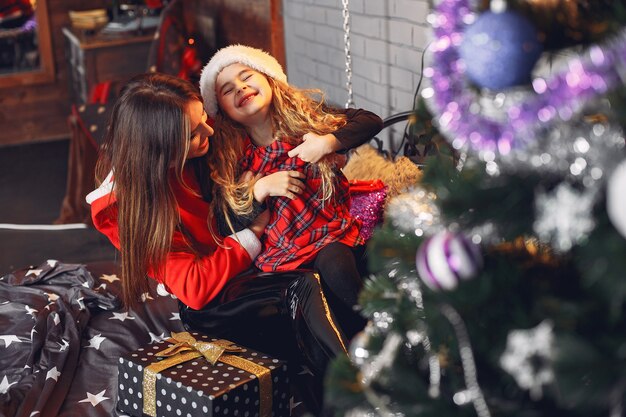 Moeder in een santa's pak met schattige dochter thuis