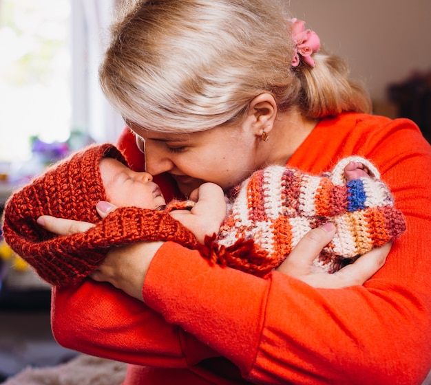 Moeder in rode trui houdt kleine pasgeboren baby op haar armen