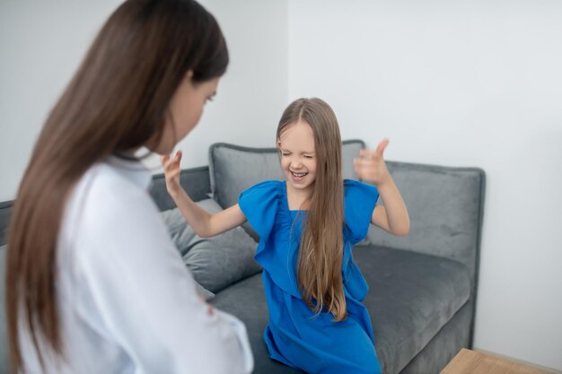 Moeder kijkt naar haar blije dochter, gebarend met gesloten ogen